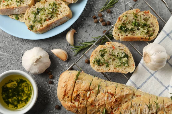 Tasty garlic bread and spices on grey background, top view — Stock Photo, Image