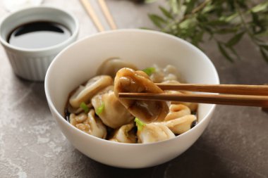 Gri arka planda, bir kase etli börek.