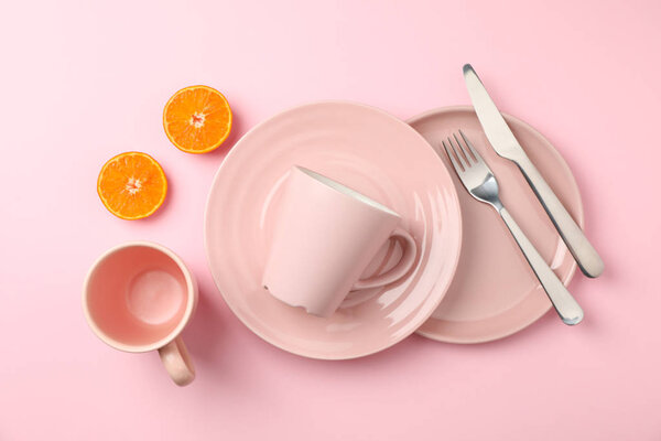 Tableware and cutlery on pink background, top view