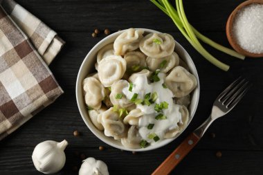 Tahta arka planda köfte, havlu, çatal ve baharatla dolu bir kâse.