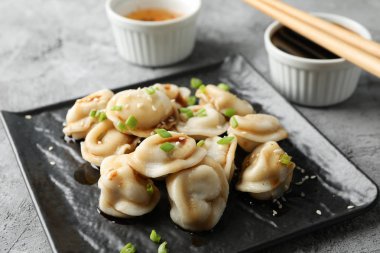 Kare tabakta hamur köftesi, sos ve yemek çubukları var.