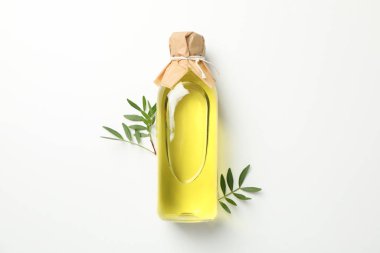 Zeytinyağlı bir şişe ve beyaz arka planda yapraklar. 