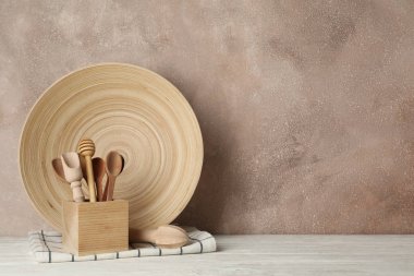 Tahta sofra takımı ve çatal bıçak takımı beyaz masada, kahverengi sırt çantasına karşı.