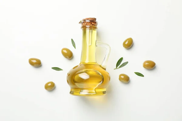 Flat lay with jug of olive oil, olives and leaves on white backg — Stock Photo, Image