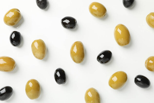Зеленые и черные оливки на белом фоне, вид сверху

