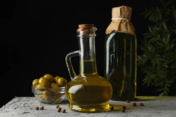 Fles en kan met olijfolie tegen zwarte achtergrond, ruimte voor — Stockfoto
