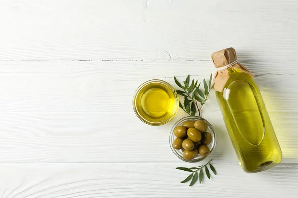 Oliwki, butelki i miski z oliwą z oliwek na drewnianym tle, top — Zdjęcie stockowe