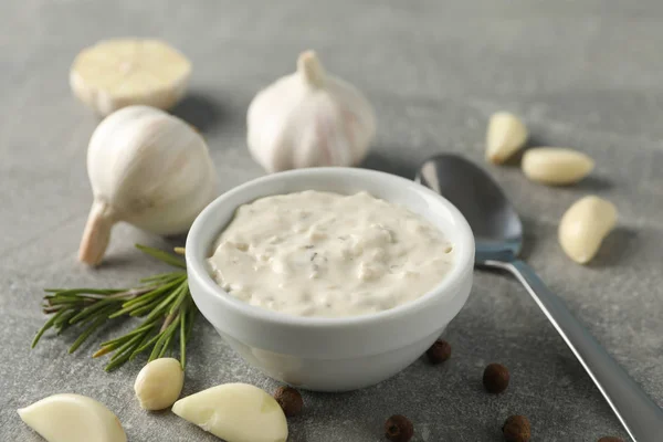 Schüssel mit Sauce, Knoblauchzwiebeln, Scheiben, Löffel, Rosmarin auf grauem Bac — Stockfoto