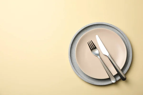 Taca z talerzem, widelcem i nożem na beżowym tle, widok z góry — Zdjęcie stockowe