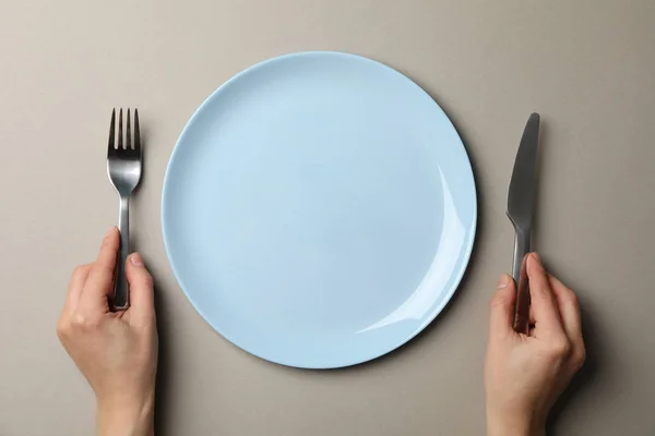 Female hands hold fork and knife on grey craft background with p — 스톡 사진
