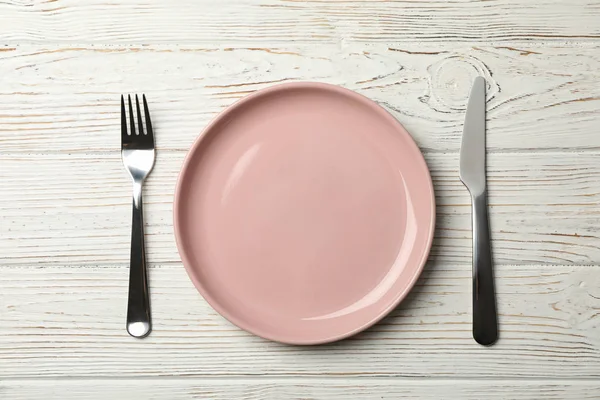 Plate, fork and knife on wooden background, top view — 스톡 사진