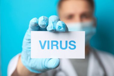 Doctor holds inscription Virus on blue background. Healthcare an