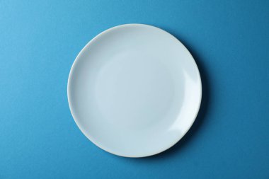 Plate on blue background, top view and space for text