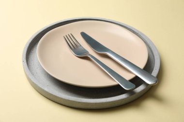 Tray with plate, fork and knife on beige background, close up