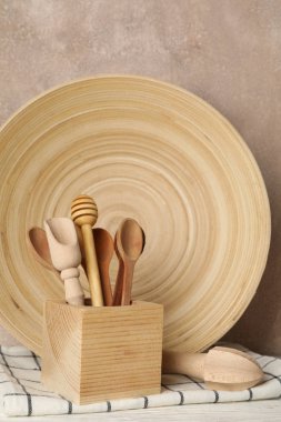 Tahta sofra takımı ve çatal bıçak takımı beyaz masada, kahverengi sırt çantasına karşı.