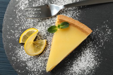 Ahşap zemin üzerinde limonlu turta dilimi olan mermer tepsi tepsisi, üst manzara