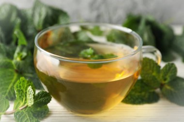 Bir fincan çay ve nane, beyaz ahşap masada, yakın.