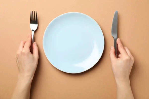 Female hands hold fork and knife on craft background with plate, — 스톡 사진