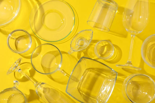 Tigelas, copos e copos em fundo amarelo, vista superior — Fotografia de Stock