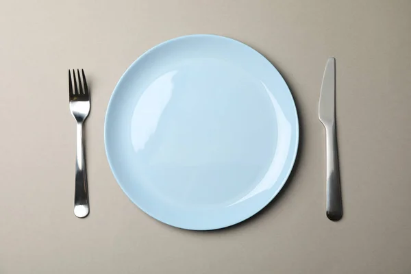 Assiette, fourchette et couteau sur fond papier gris, vue de dessus — Photo