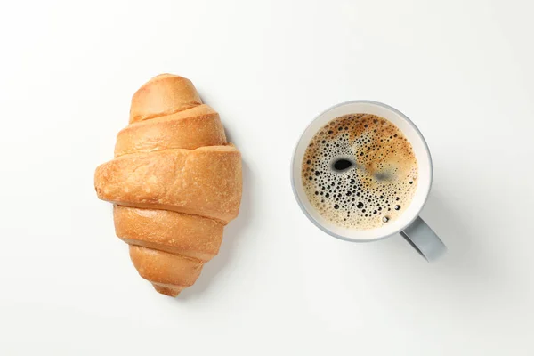 Croissant and cup of coffee on white background, top view — Stock Photo, Image