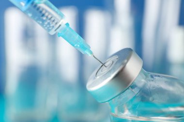 Medical syringe of vaccine, injection on blue background. Corona