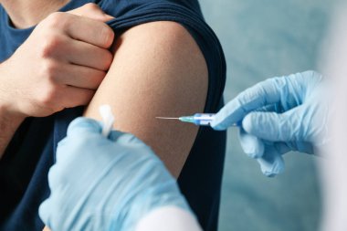 Doctor does an injection patient on blue background. Coronavirus