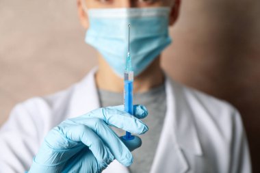 Doctor holds medical syringe of vaccine, injection on brown back