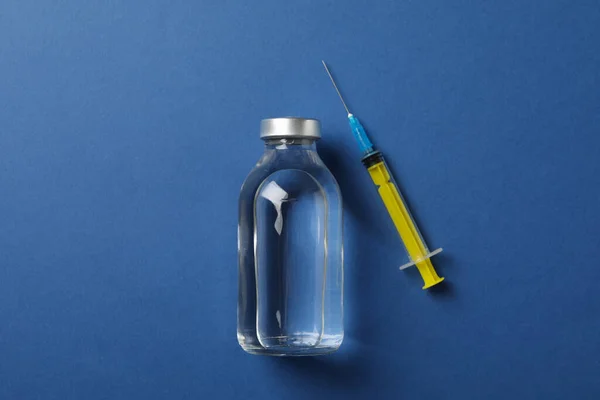 Bottle of vaccine and syringe on blue background, top view, spac — 图库照片