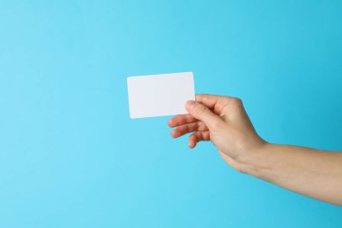 Mavi arka planda boş bir kartvizit tutan kadın.