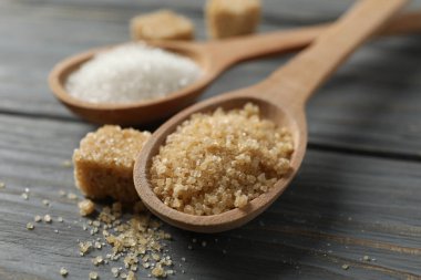 Tahta arka planda şekerli kaşıklar, yaklaşın.