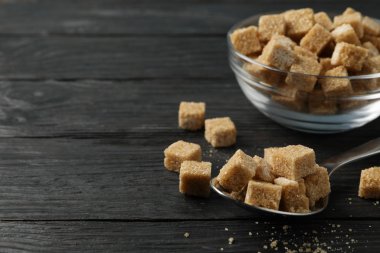 Tahta arka planda kahverengi şekerli kase ve kaşık, yakın plan.