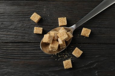Tahta zemin üzerinde şeker küpleri olan kaşık, üst görünüm