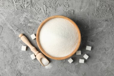 Gri arka planda şekerli kase ve kepçe, üst görünüm