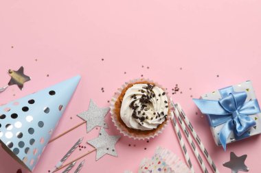 Üzerinde kek ve doğum günü aksesuarları olan pembe bir kompozisyon.