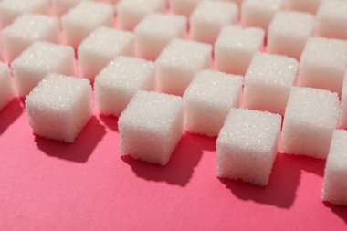 Many sugar cubes on pink background, close up