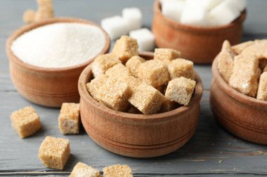 Tahta arka planda farklı şekerli kaseler, yakın plan.