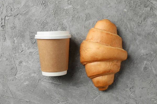 Taza de papel de café y croissant sobre fondo gris, espacio para —  Fotos de Stock