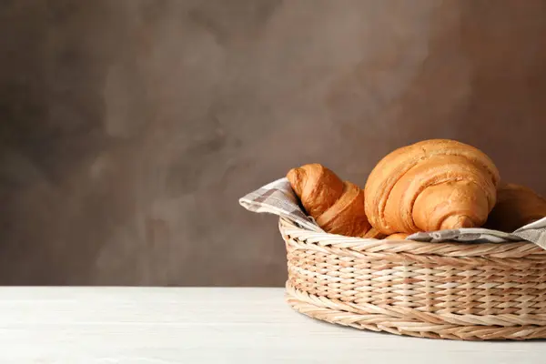 Cesto di vimini con cornetti su tavolo di legno, spazio per testo — Foto Stock