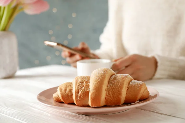 Assiette avec croissant sur table en bois, fermer. Jeune femme tenir — Photo