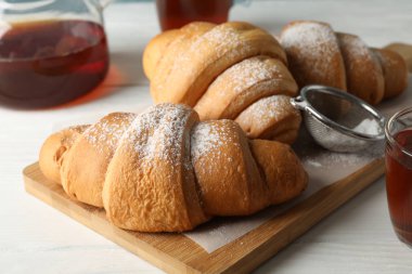 Lezzetli kruvasan ve fincanlar, ahşap arka planda çay, kapa çeneni.