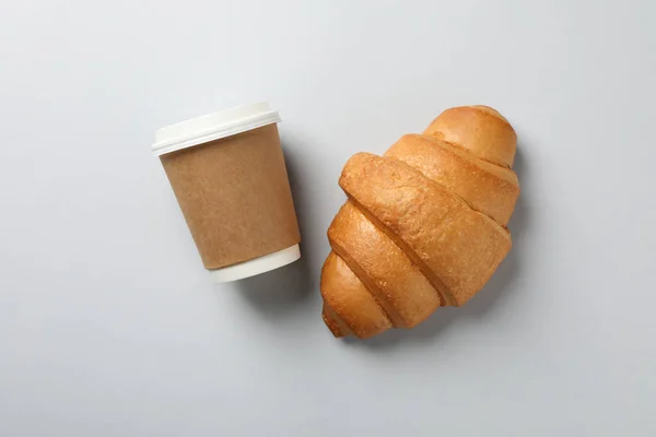 Croissant y taza de papel de café sobre fondo gris, espacio para —  Fotos de Stock