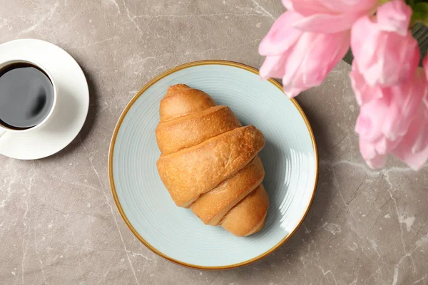 Placa com croissant em fundo cinza com tulipas e xícara de c — Fotografia de Stock