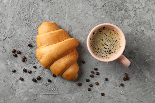 Taza de café y croissant sobre fondo gris, vista superior —  Fotos de Stock