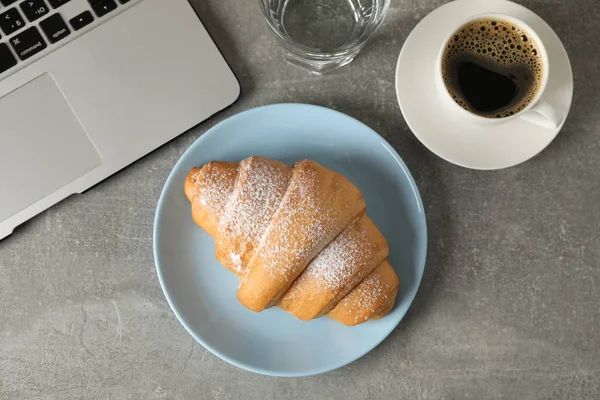 Composition with croissant and computer on grey background, top — Stock Photo, Image