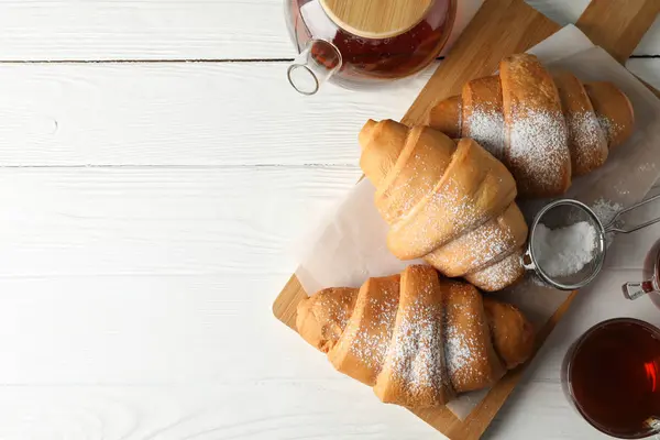 Leckere Croissants und Tassen mit Tee auf Holzhintergrund, Top vie — Stockfoto