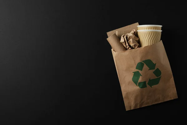 装废纸的袋子和黑色背景、空间上的回收标志 — 图库照片