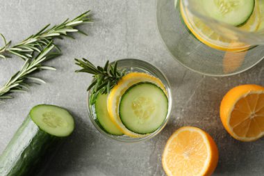 Gri masada salatalık suyu olan sürahi ve cam, üst manzara.