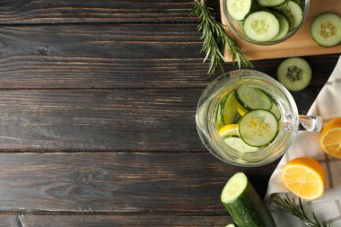 Tahta arka planda sürahi içinde salatalık suyu olan kompozisyon, üst