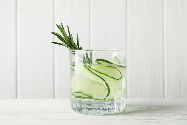Glass with infused cucumber water on wooden background, close up